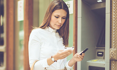 Woman looking at card and receipt in front of ATM