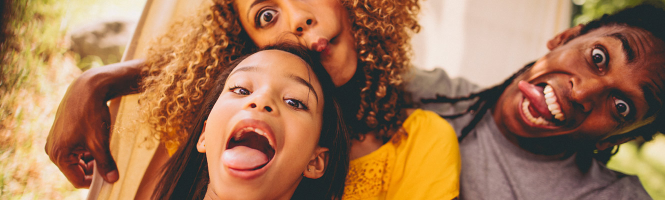 Parents with young daughter making faces and taking a selfie.